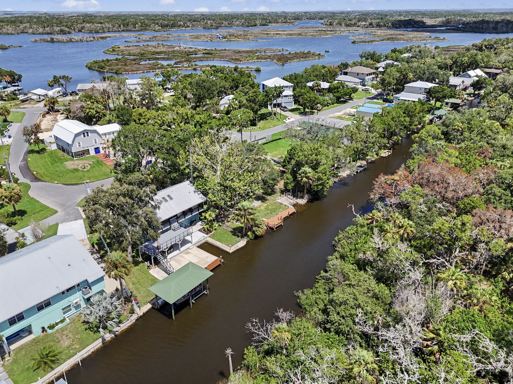 Rooftops, palms and dark tidal water at The Rusty Hook Riverhouse, Old Homosassa, Florida