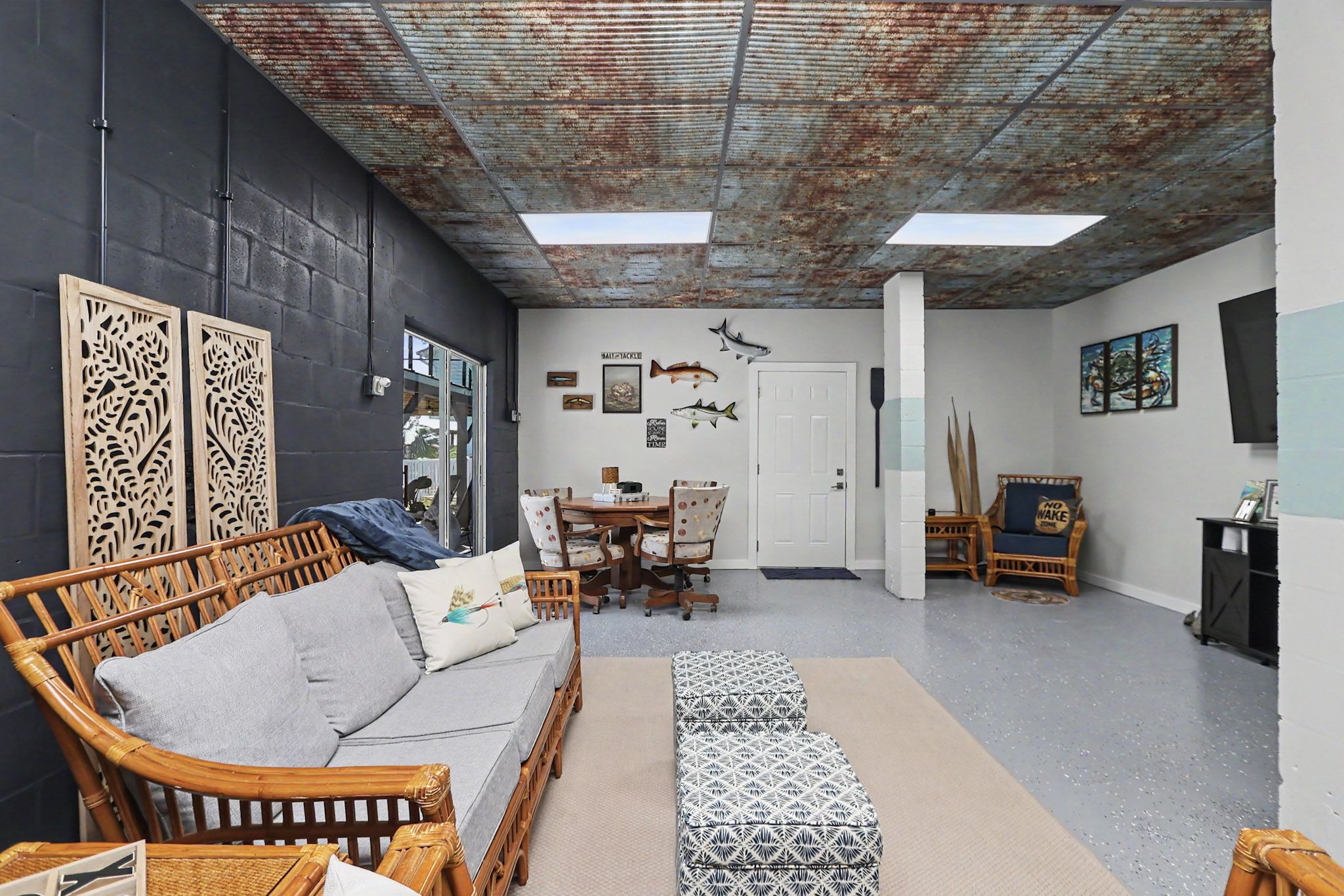 Wide view of the navy ground-floor lounge with rattan seating, television wall and games area