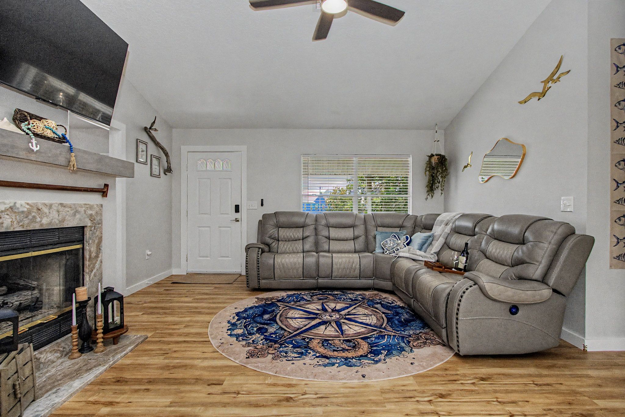 Living room with a fireplace, sectional seating, nautical details and a navy compass rug