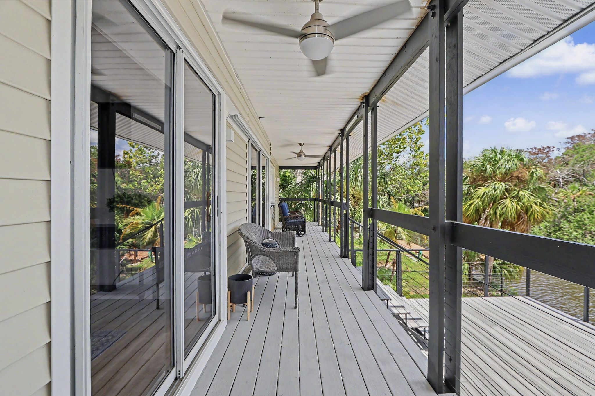 Long open porch running the length of the house with wicker chairs and slow ceiling fans